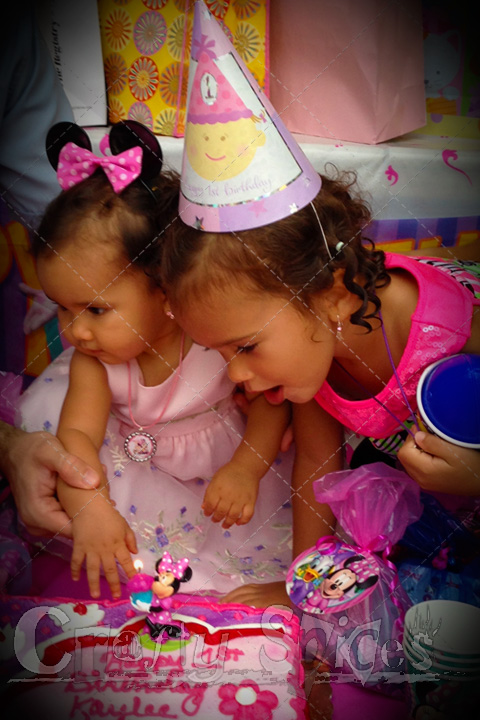 Kaylee blowing the candle and big sister Kira helping her